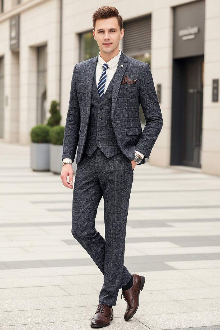 Person wearing a gray checkered suit with a striped tie, standing against a marble wall.