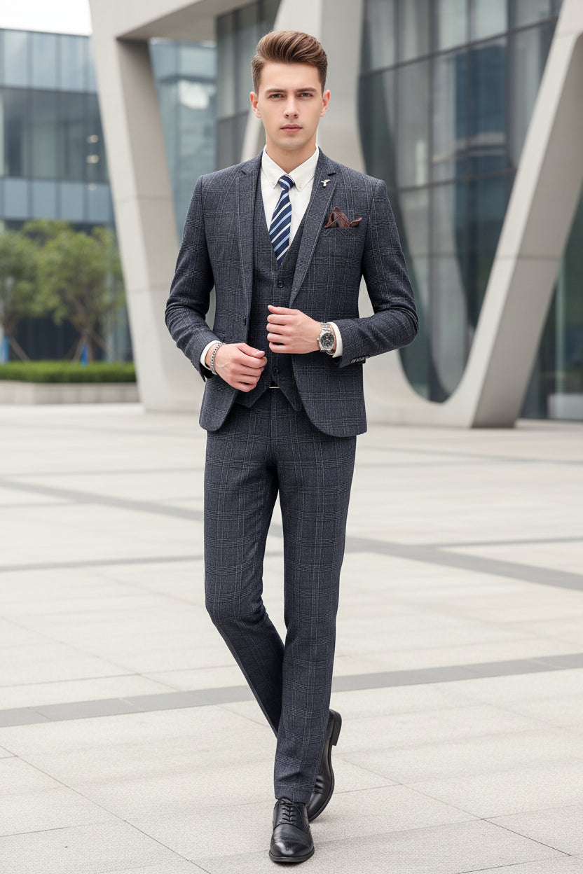 Person wearing a gray checkered suit with a striped tie, standing against a marble wall.