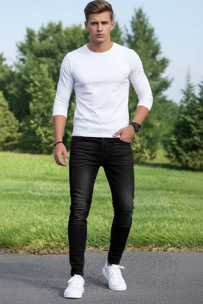 Person wearing black jeans and white sneakers on a grassy background