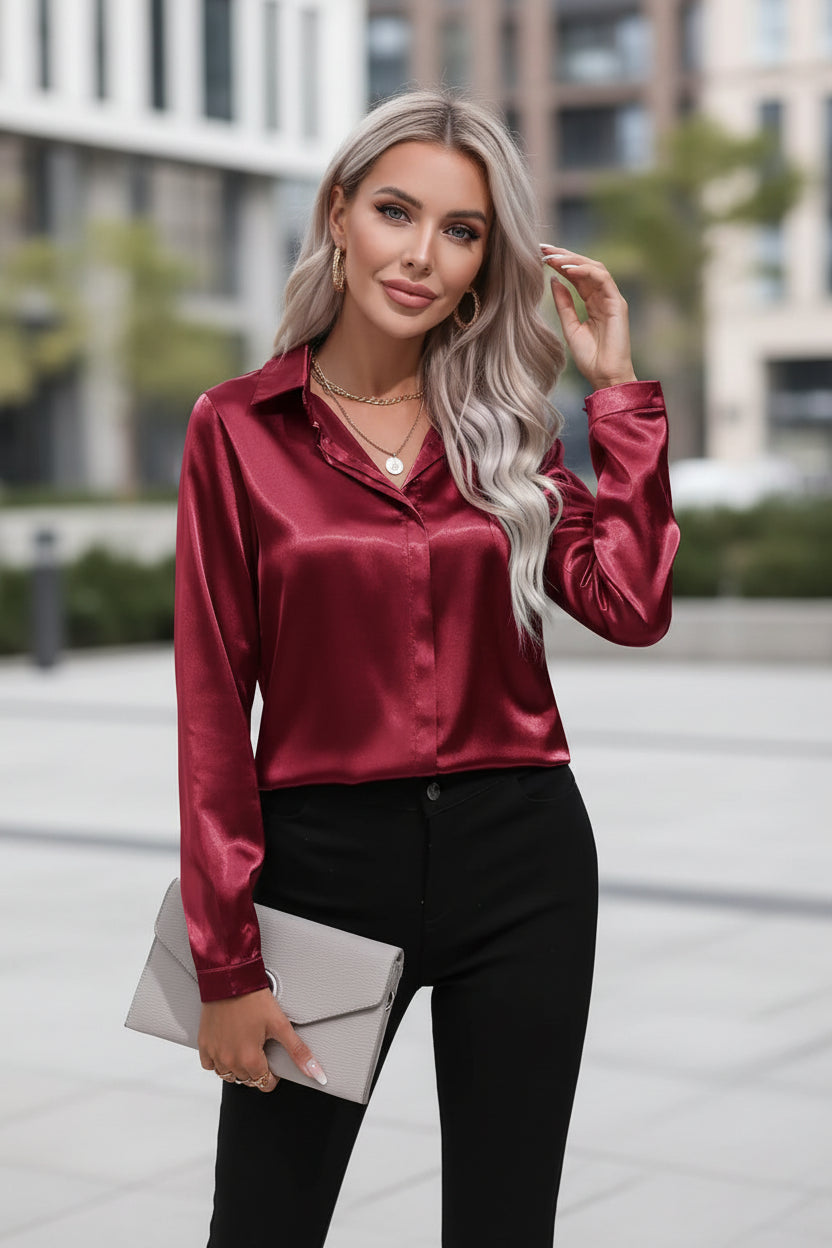 Person wearing a burgundy satin shirt with black pants on a white background