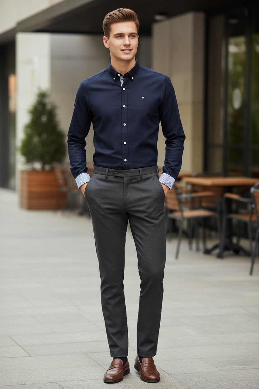 Folded navy blue dress shirt with white buttons on a light gray background