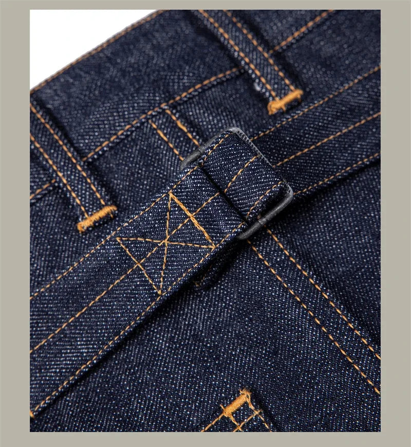 Close-up of blue denim fabric with orange stitching on a gray background