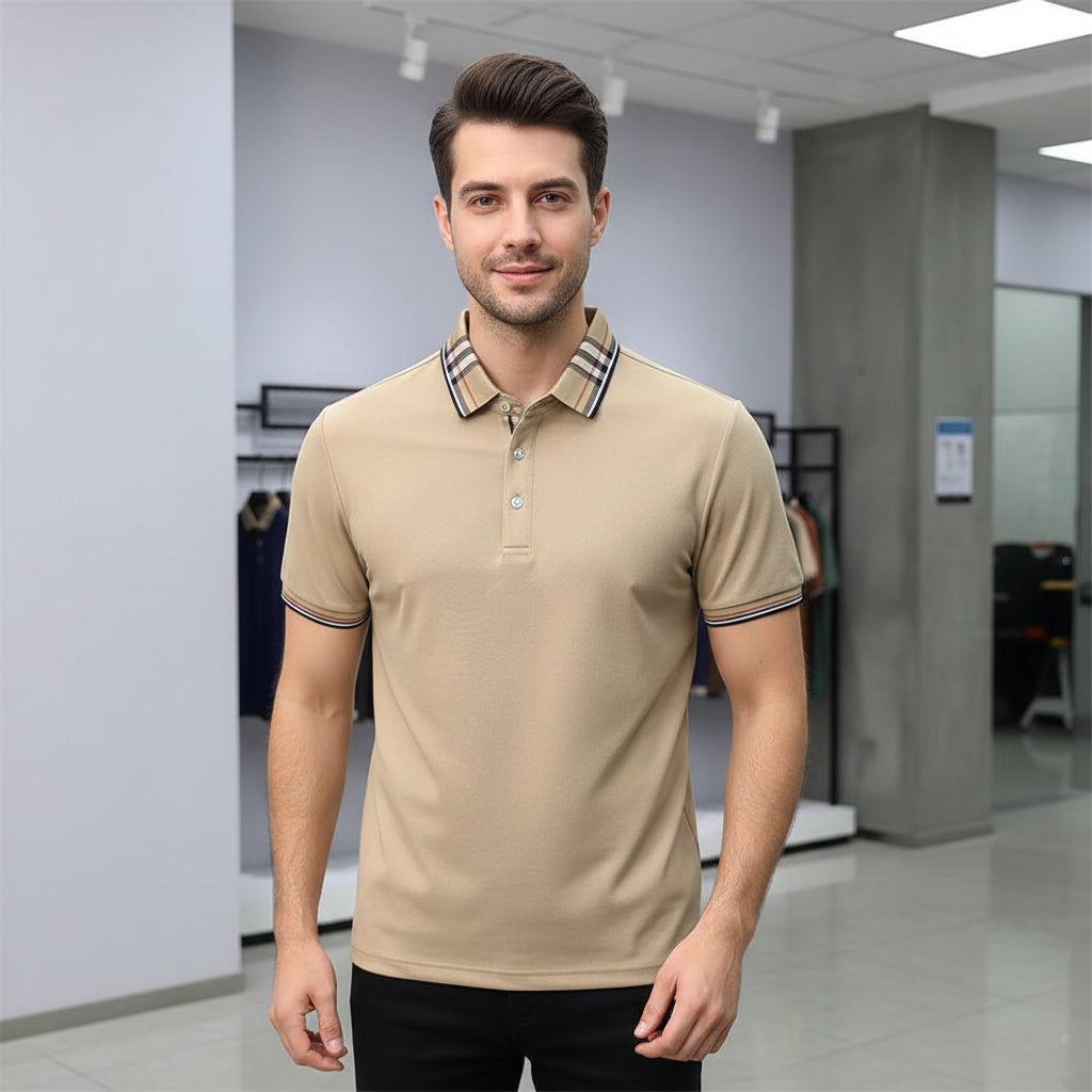 Beige polo shirt with plaid collar held by a hand against a blurred indoor background