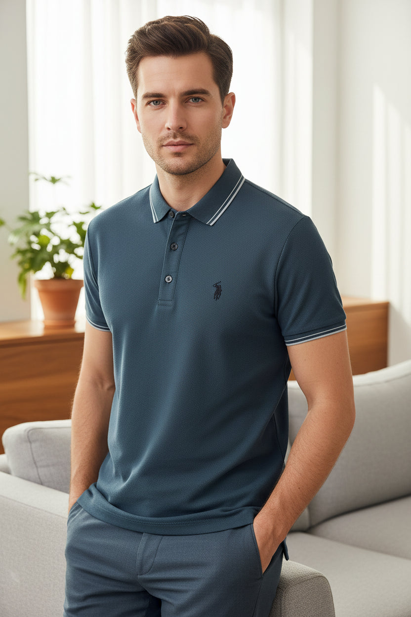 Blue polo shirt with white trim held by a hand against a blurred indoor background