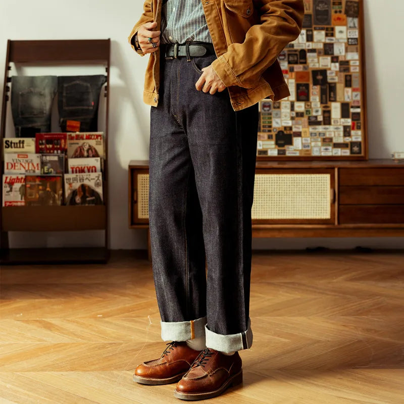 Person wearing a brown jacket, blue jeans, and brown shoes in a room with wooden floor and wall decorations.
