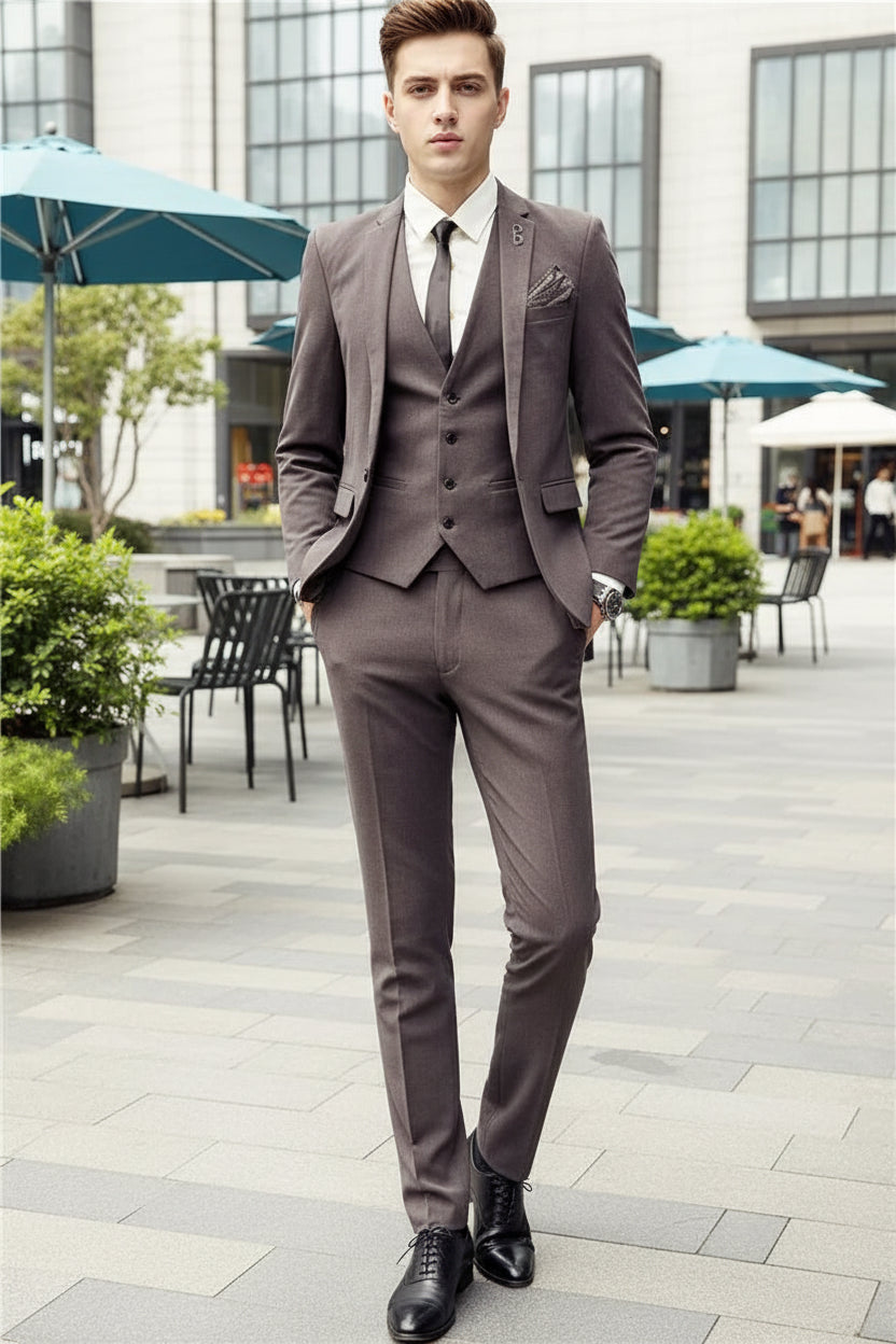 Man wearing a brown suit standing in front of a store with glass windows.