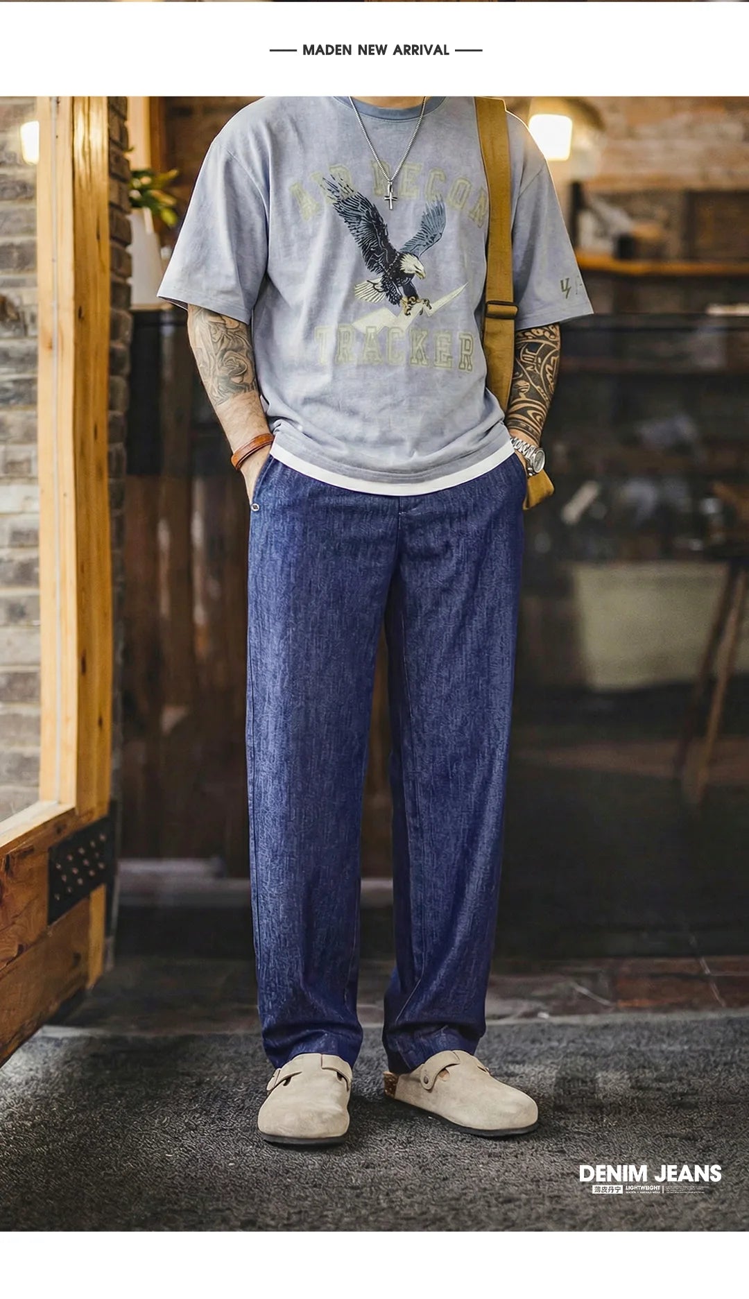 Person wearing a graphic t-shirt and blue jeans standing in a casual setting.