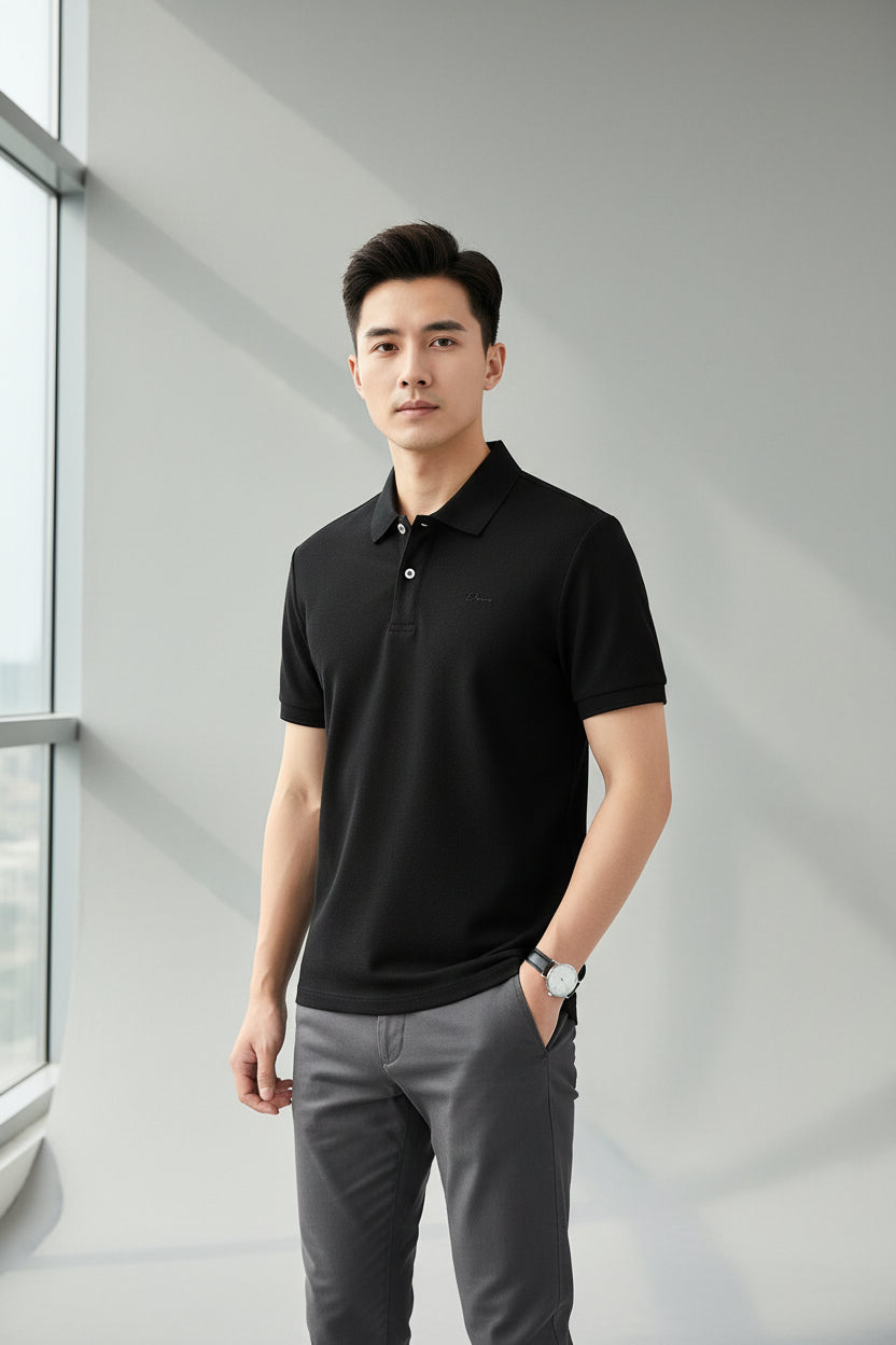 Black polo shirt with striped collar held by a hand, with more shirts in the background.