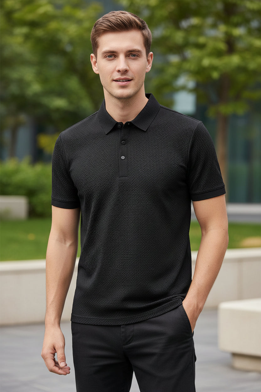 Black textured polo shirt on a hanger with a hand touching it