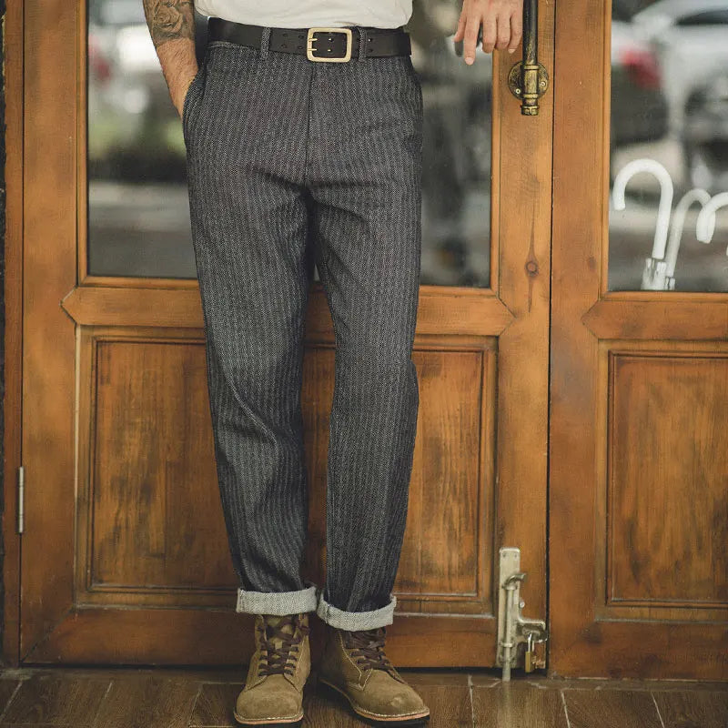 Person wearing gray checkered pants and brown boots standing in front of a wooden door.