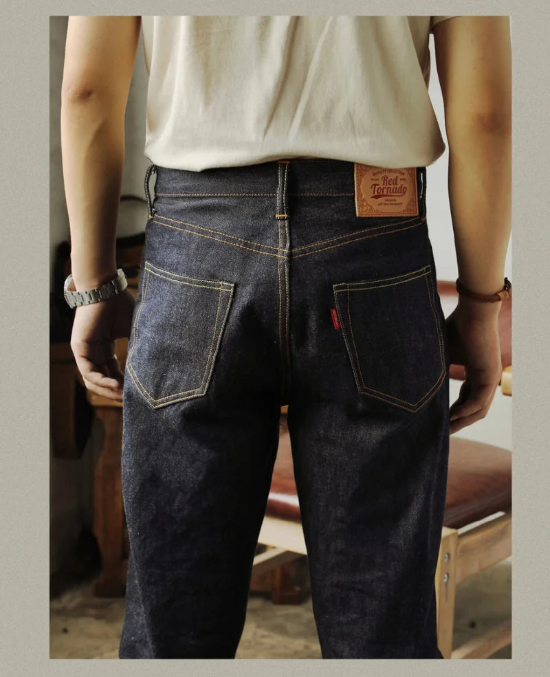 Person wearing dark blue jeans with a visible brand label, standing indoors.