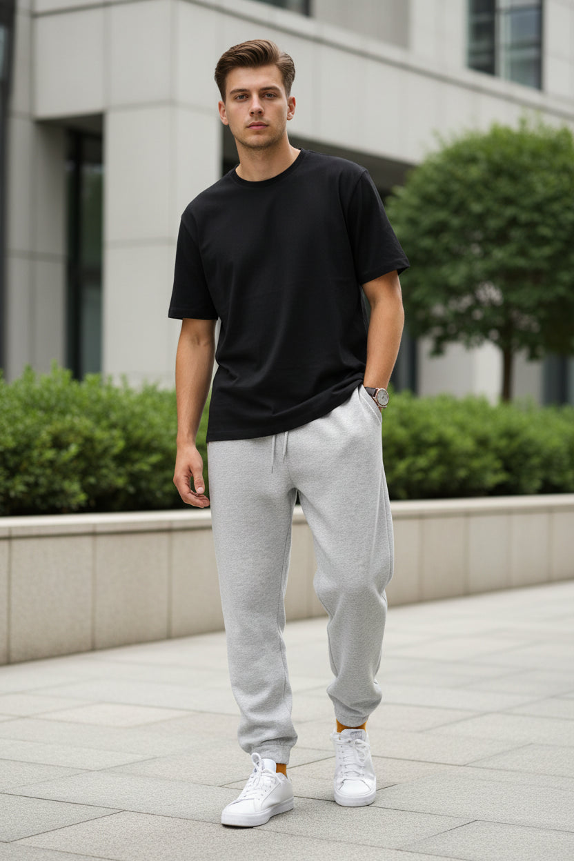 Person wearing gray sweatpants and white sneakers against a plain background