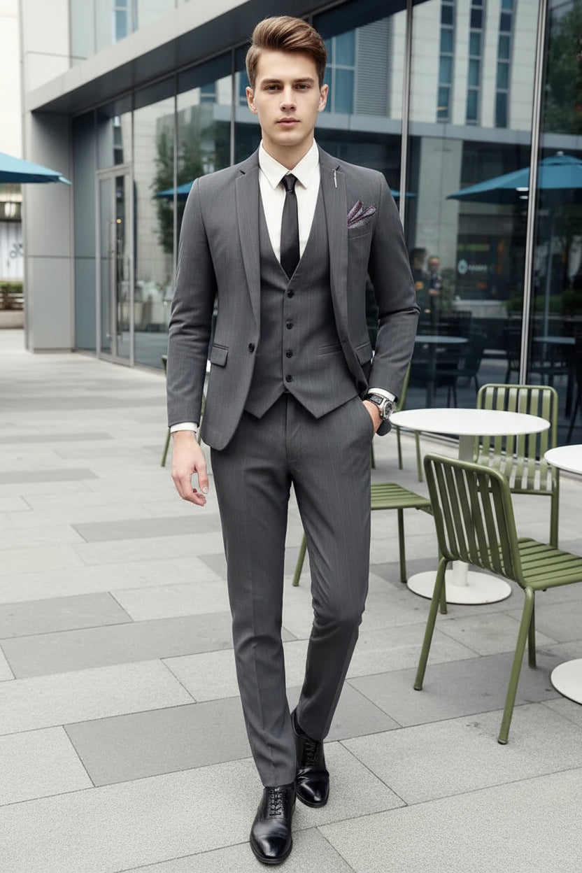 Person wearing a gray suit with a white shirt and black tie outdoors.