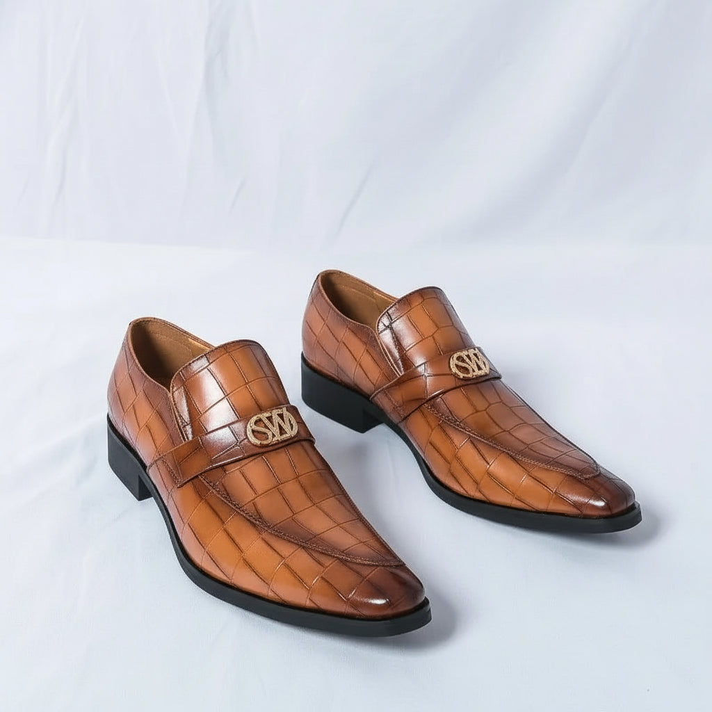 Brown leather shoes with a crocodile pattern worn by a person on a light gray background