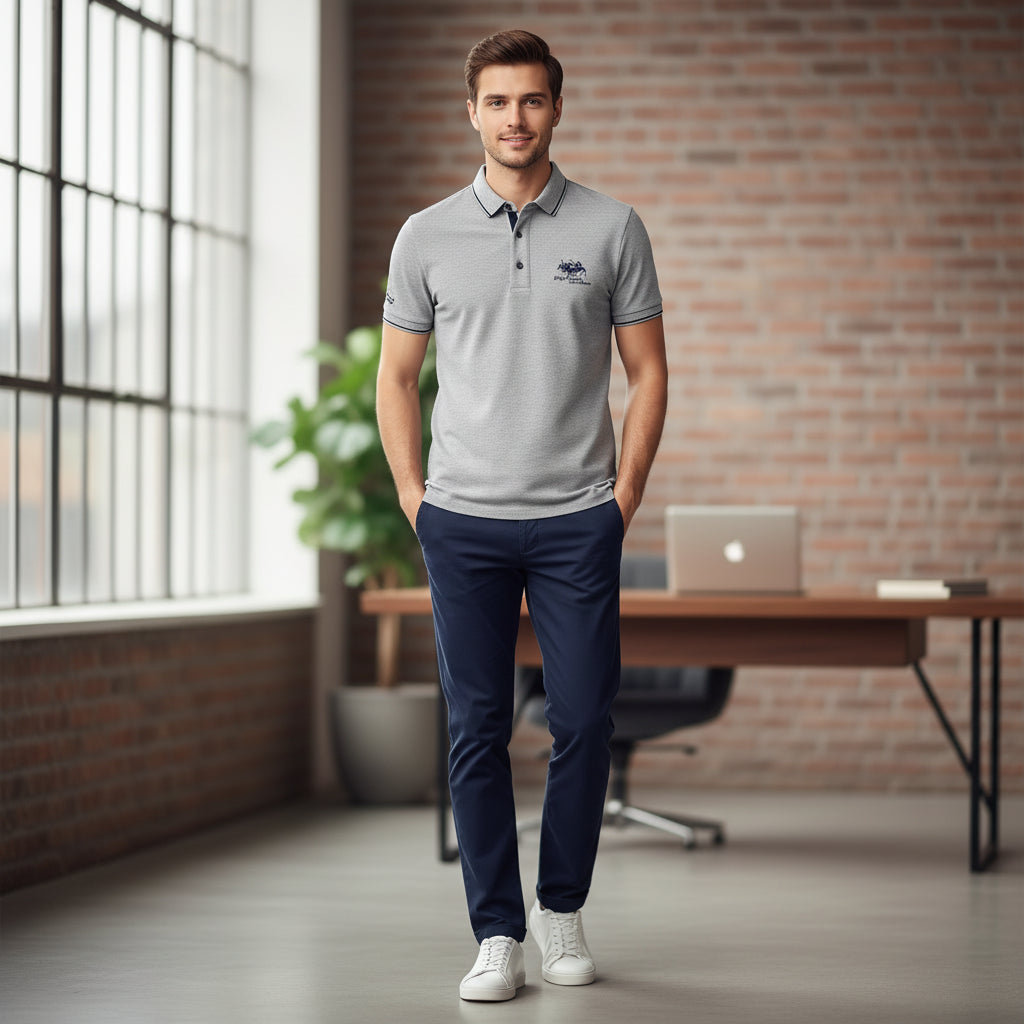 Folded gray polo shirt with brand logo on a dark surface, accompanied by a watch.