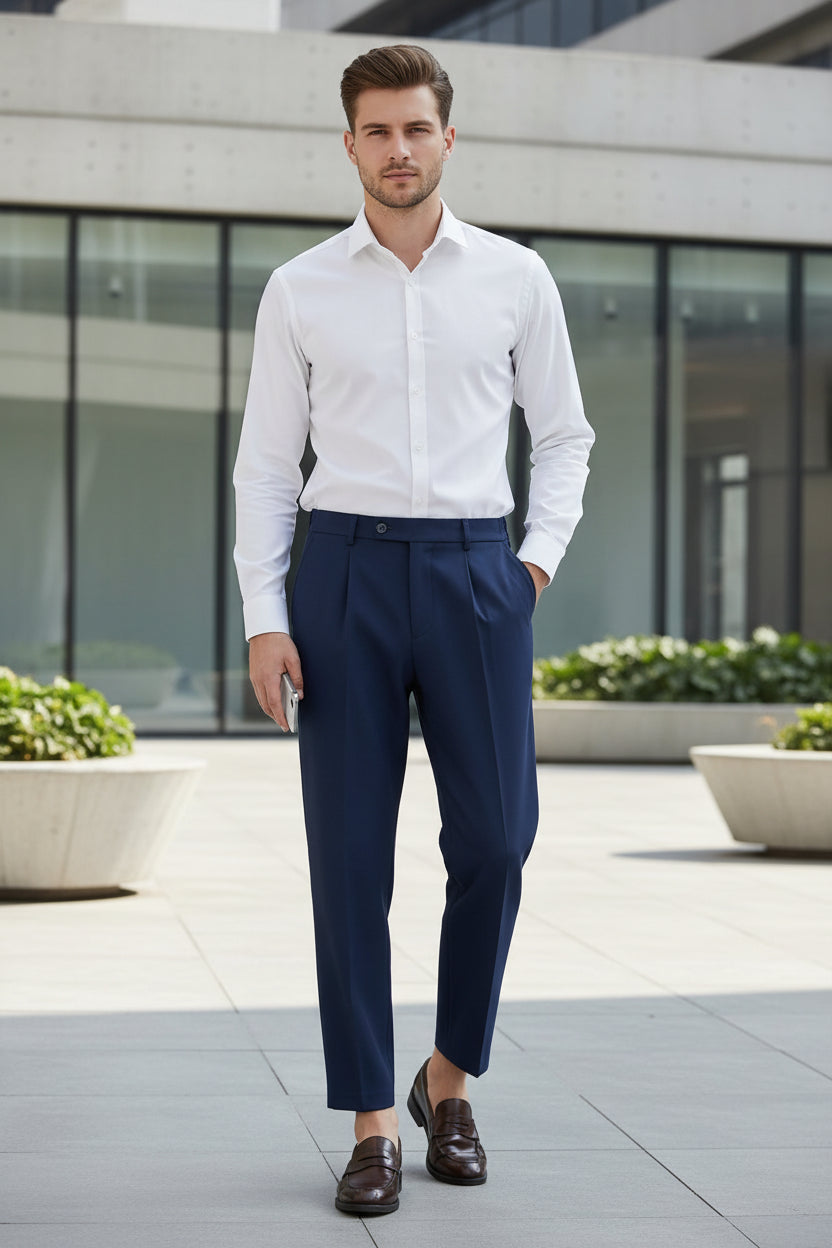 Man wearing a white shirt and navy pants in a modern hallway.