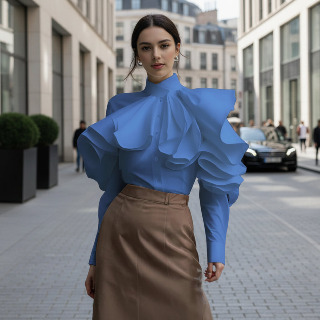 Person wearing a blue blouse with ruffled details on a city street.