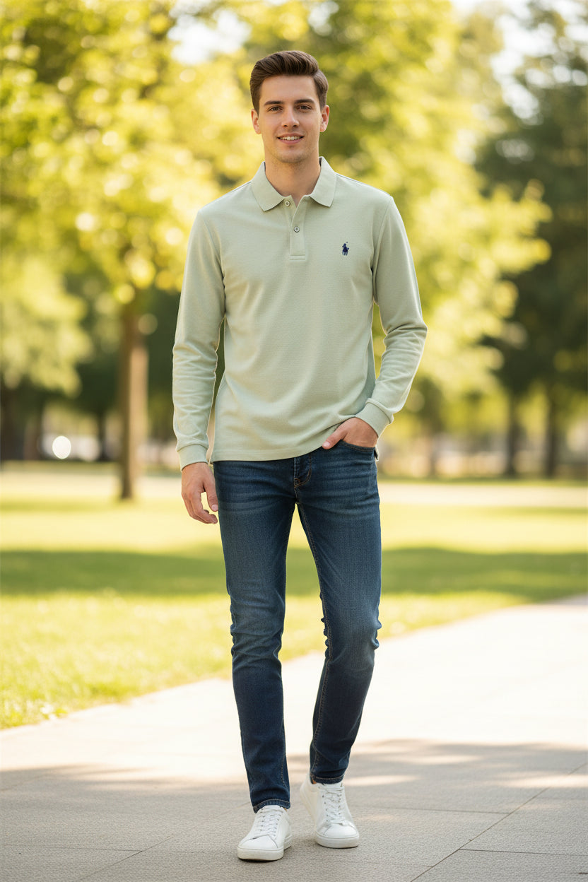 Light green polo shirt with a brand logo held by a hand, on a rack of other shirts in the background.