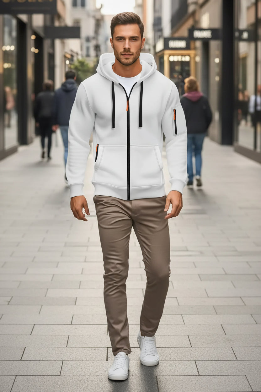 White hoodie with black zippers and orange accents worn by a person on a city street.