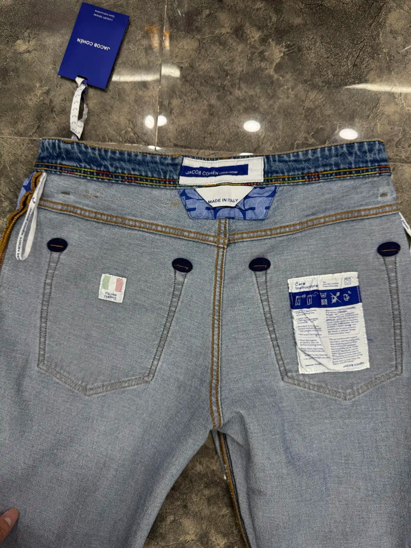 Gray jeans with tags on a reflective surface
