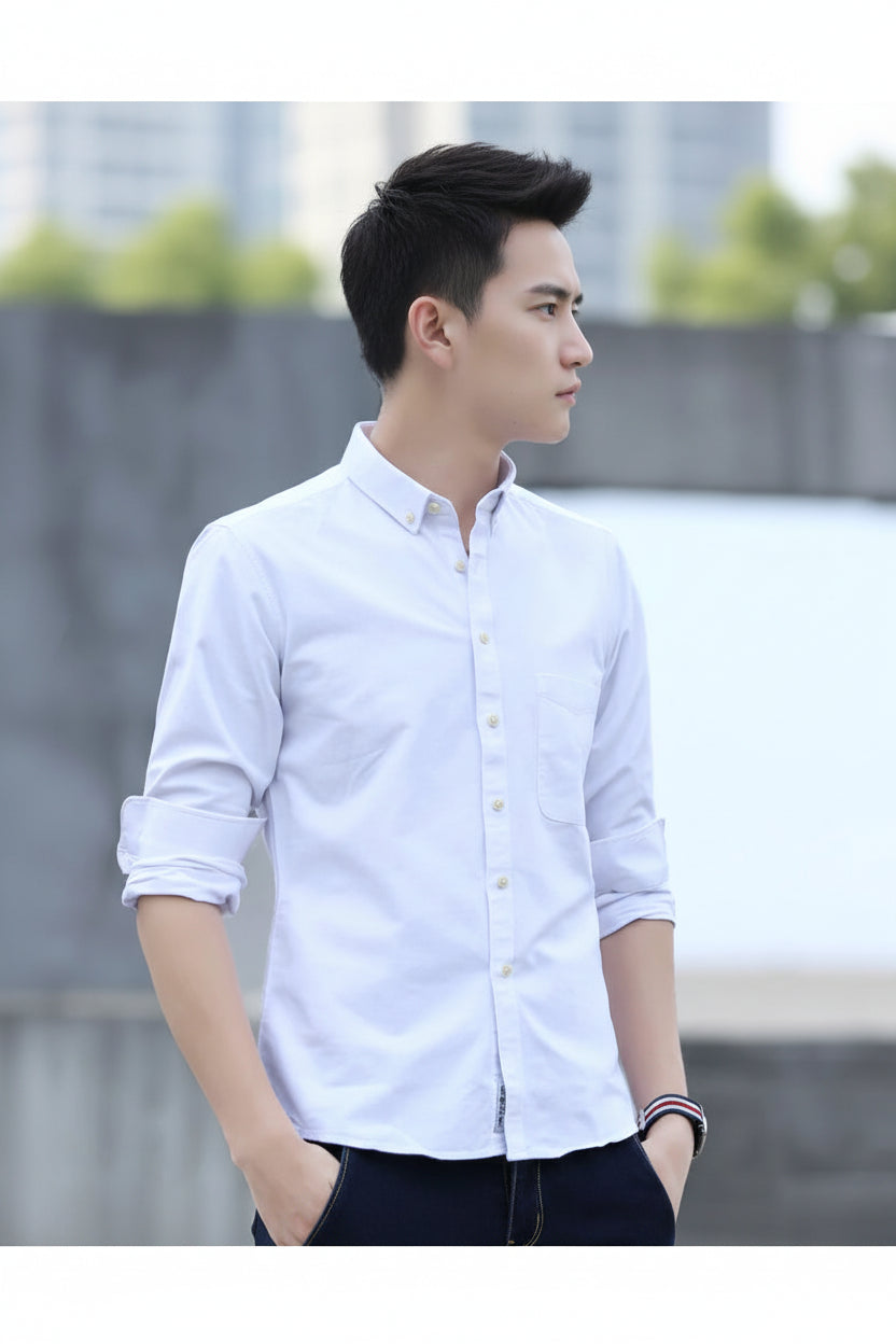 Person wearing a white button-up shirt with rolled-up sleeves against a blurred background