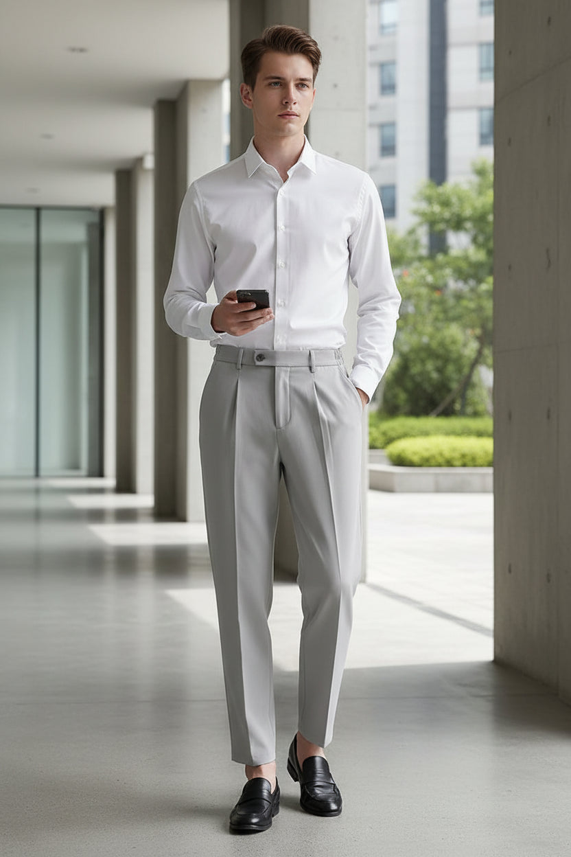 Man in a white shirt and gray pants standing in a concrete hallway.