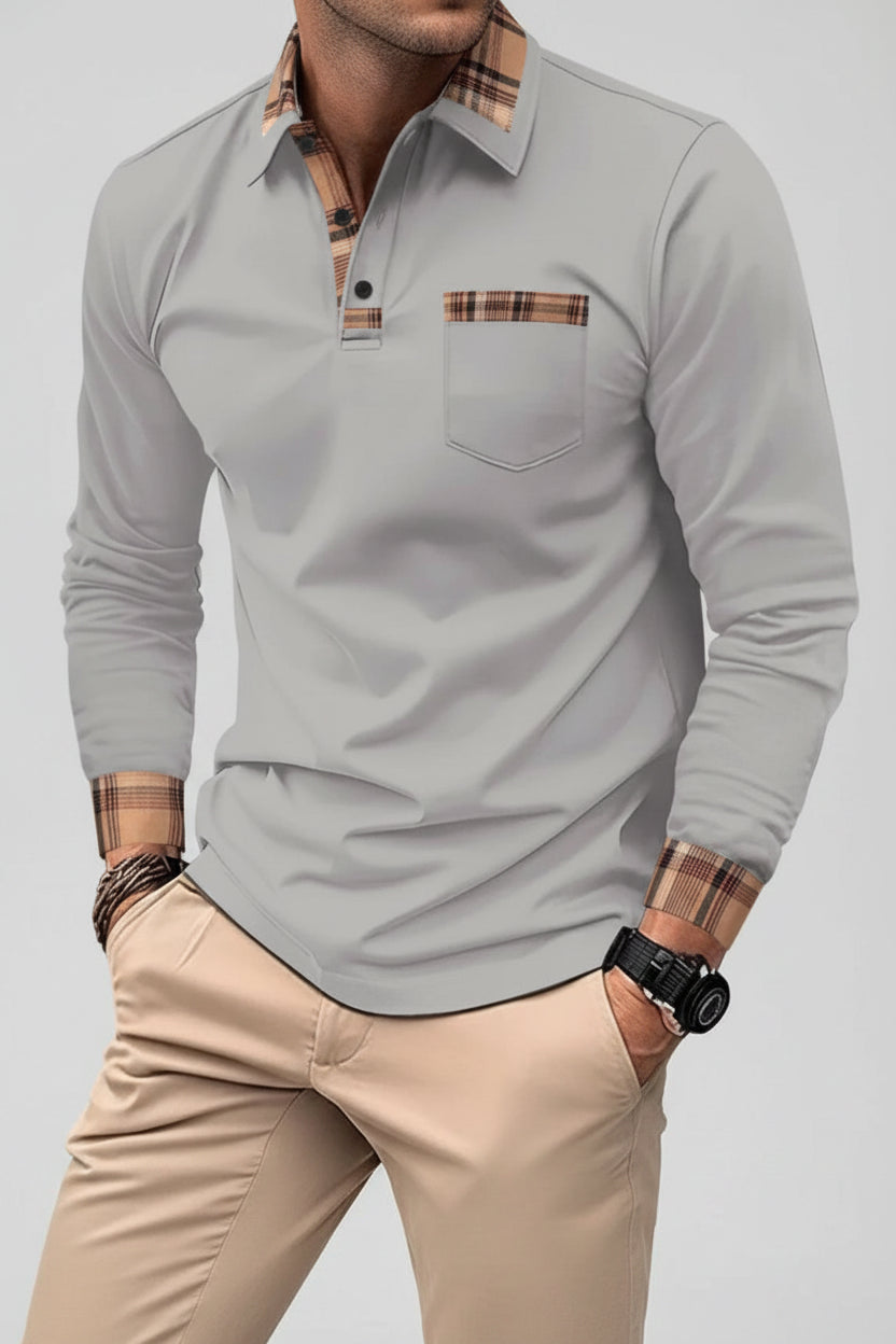 Man wearing a gray long-sleeve polo shirt with plaid accents on a city street.