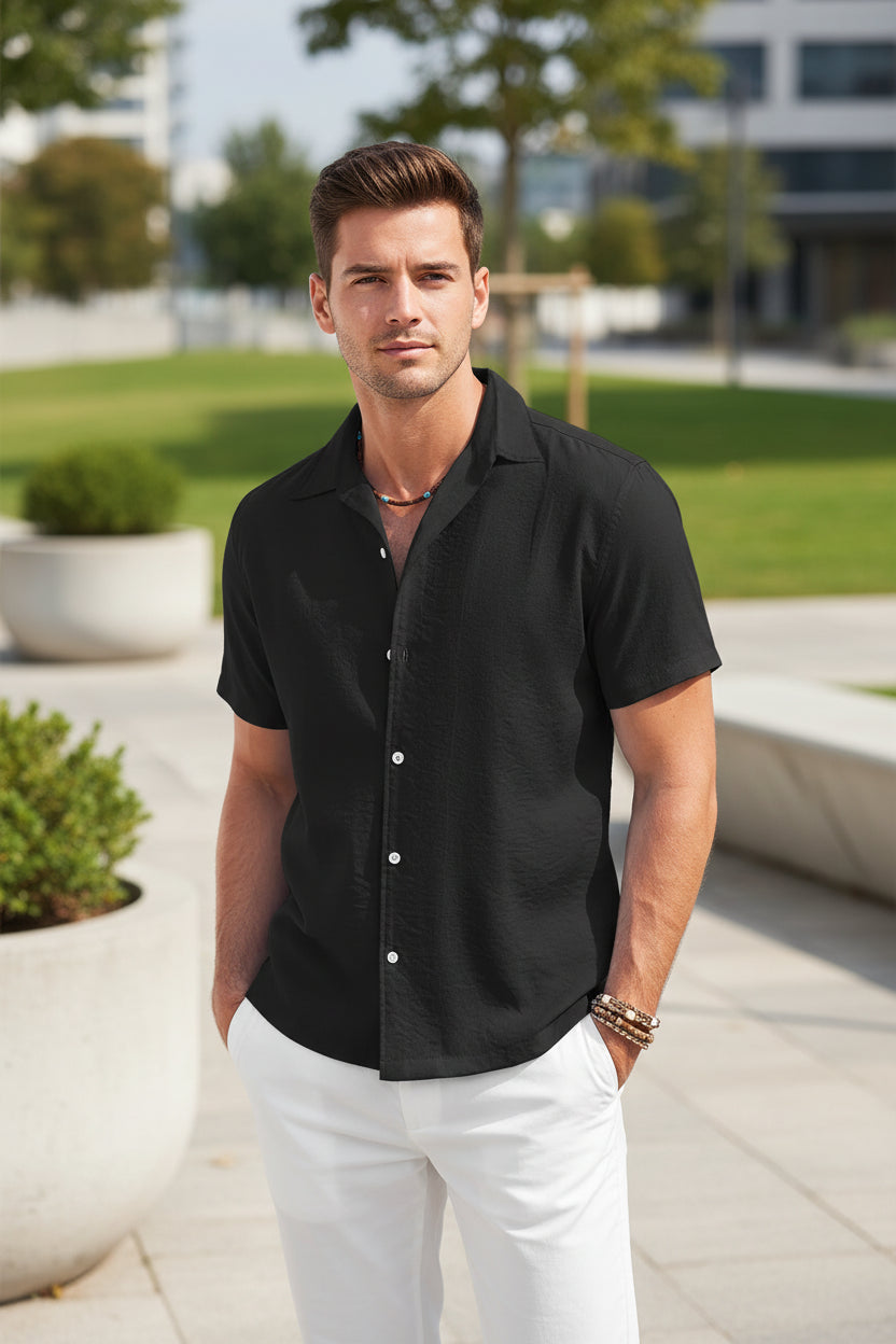Man wearing a black short-sleeve button-up shirt outside