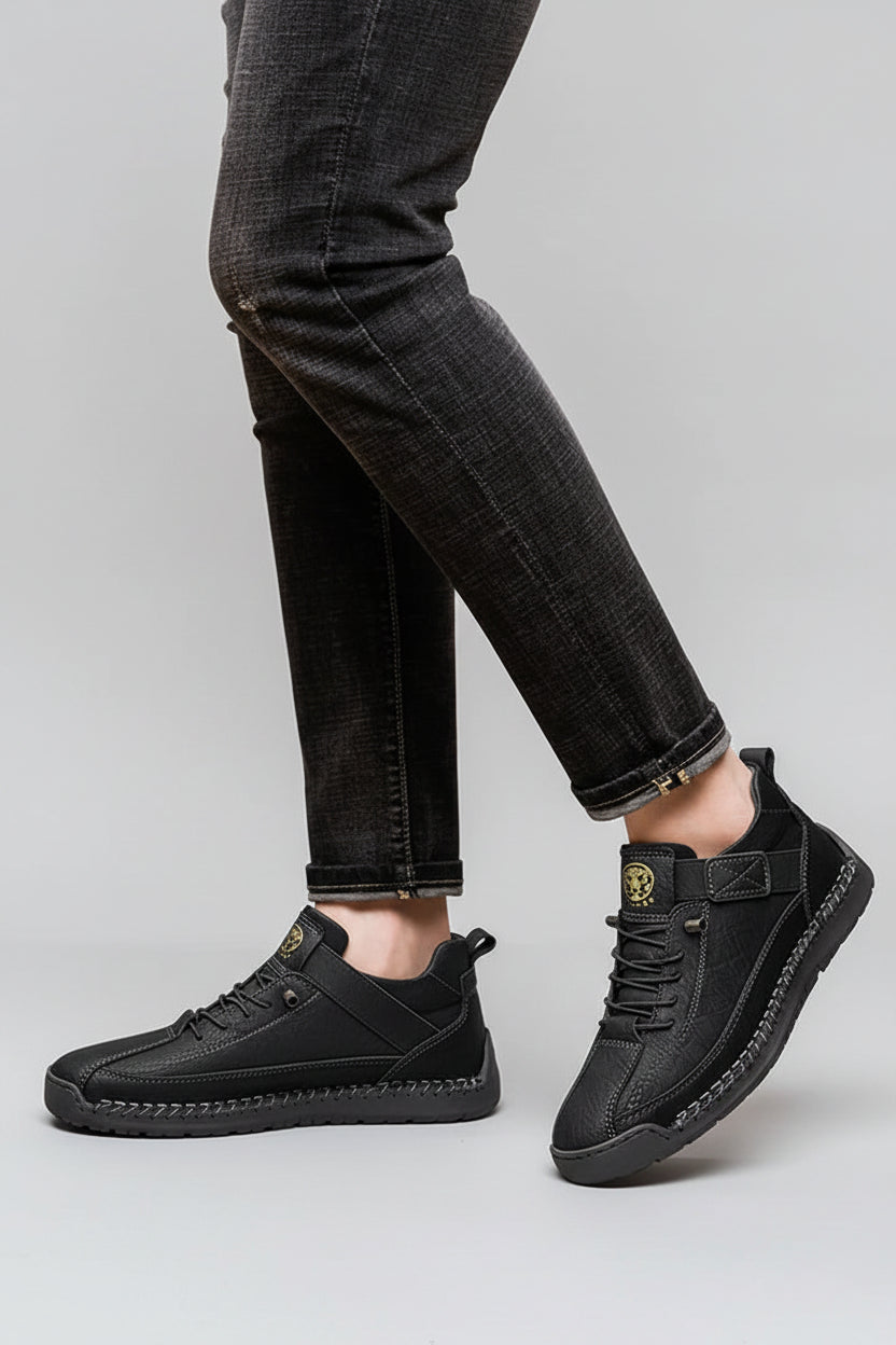 Black casual shoes worn with black pants on a beige background