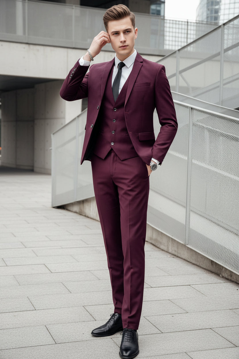 Man wearing a burgundy suit with a white shirt and black tie against a metallic background