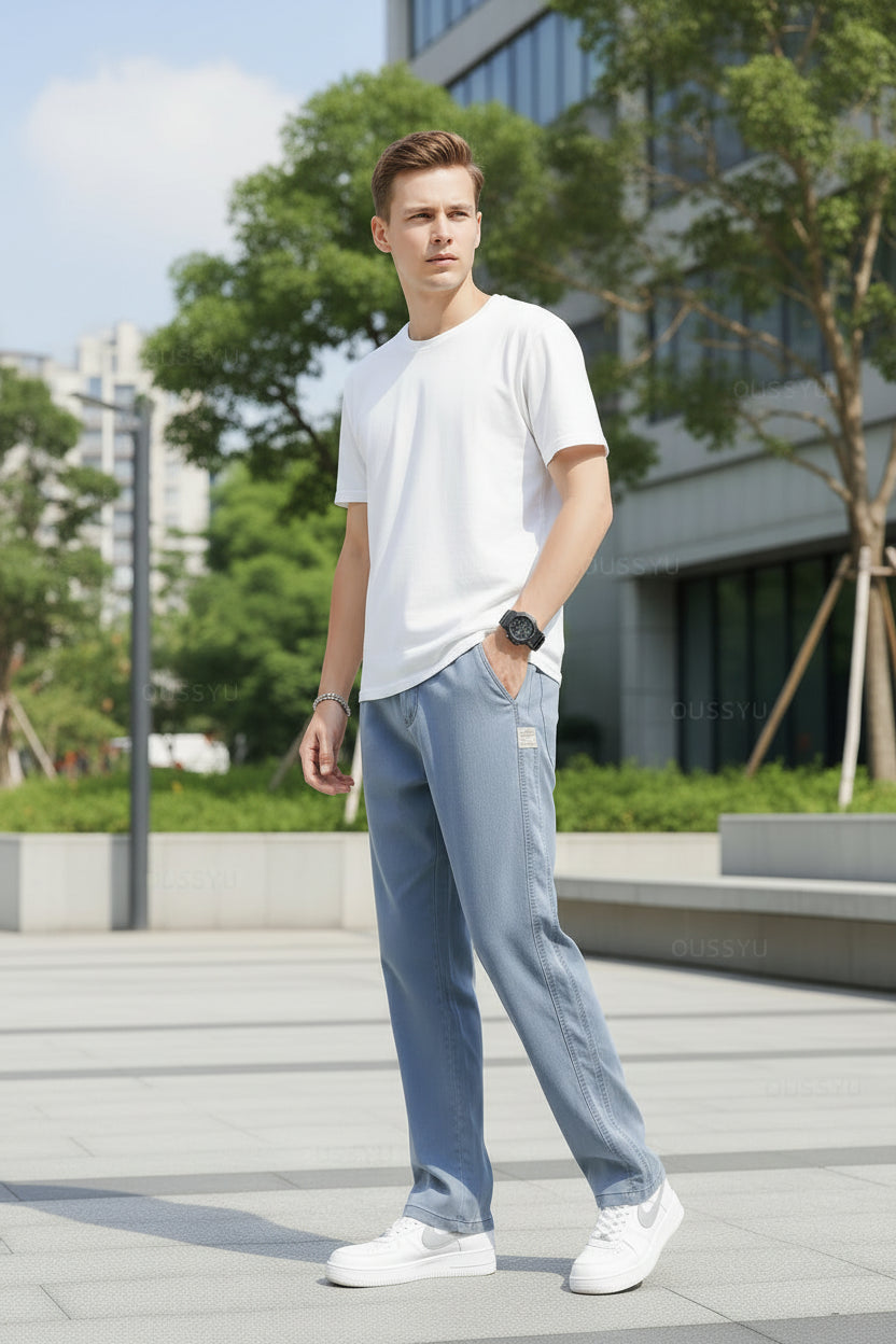 Person wearing light blue jeans and white sneakers on a gray background
