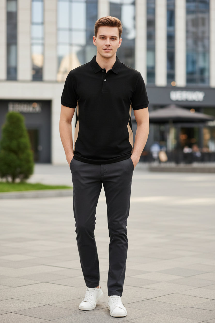 Black polo shirt on a hanger with a hand holding it, against a blurred indoor background.