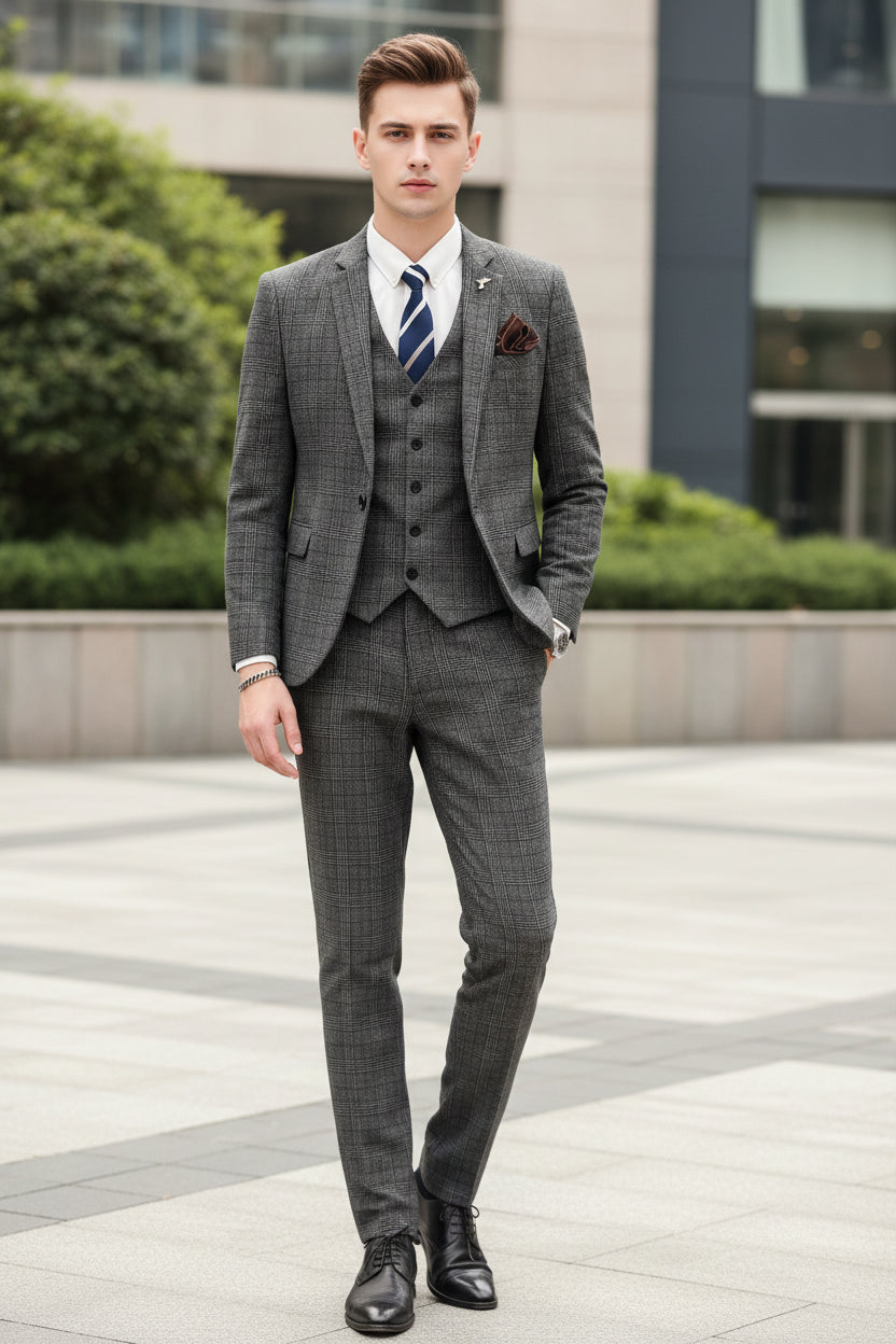 Person wearing a gray checkered suit with a white shirt and blue tie, standing against a marble wall.