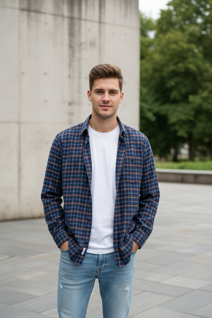 Blue and brown plaid shirt on a hanger with a hand touching it