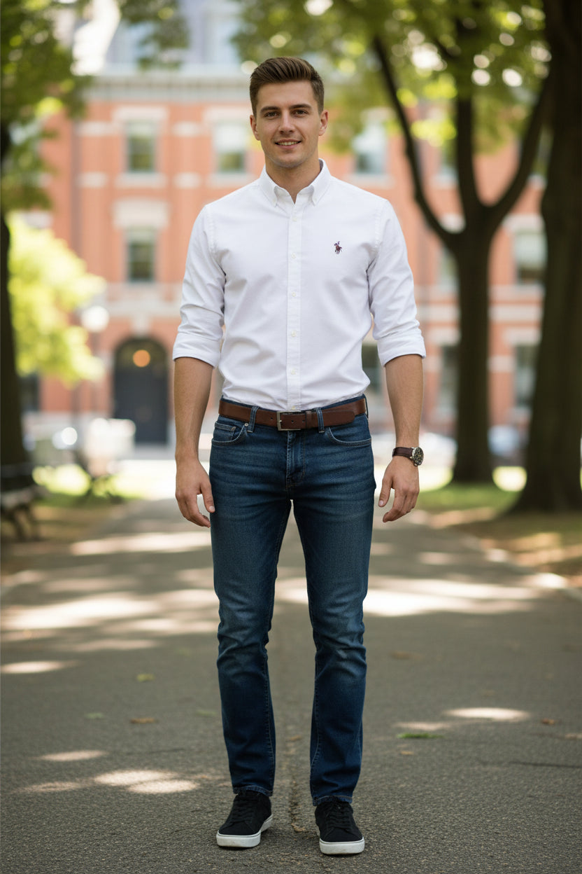 Folded white dress shirt with a small embroidered logo on a gray surface