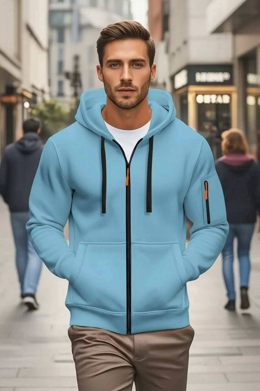 Man wearing a light blue hoodie with black zipper and orange accents in an urban setting