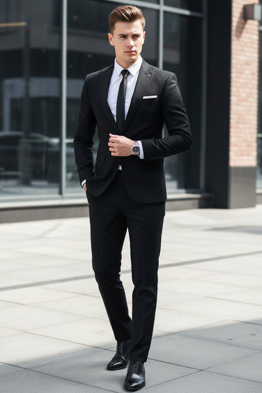 Gray suit with white shirt and black tie worn by a person, standing against a neutral background.