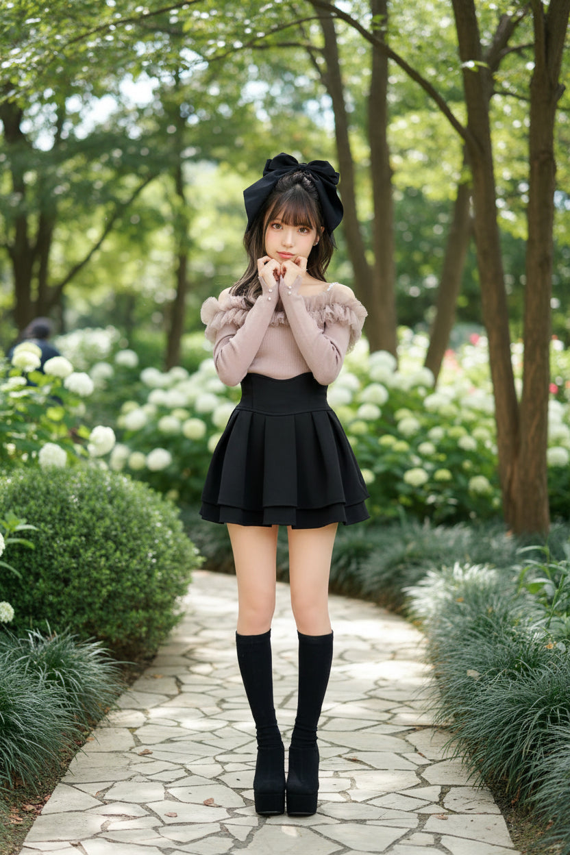 Person wearing a black skirt and knee-high socks with decorative bows on a white wall.