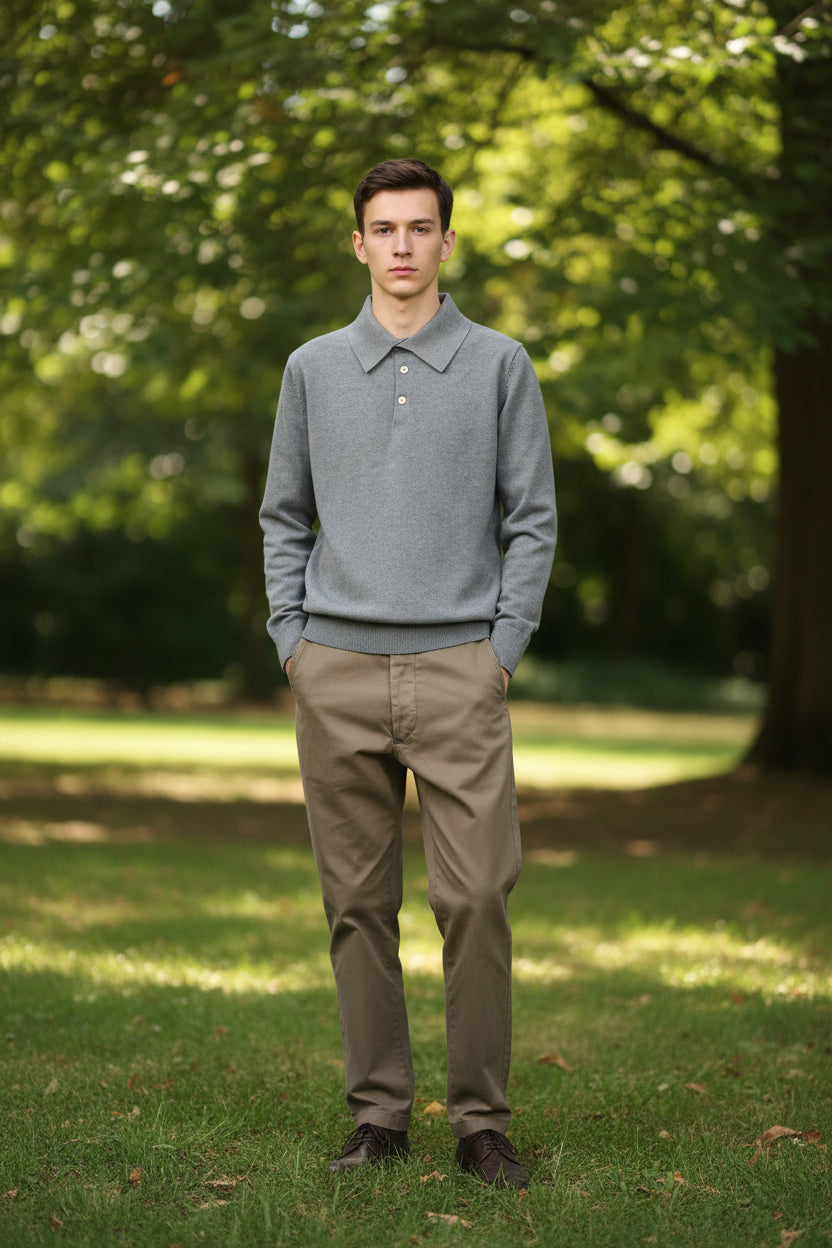 Person wearing a gray knit polo sweater with a green background