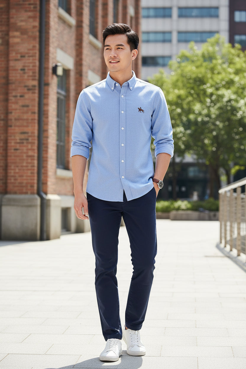 Folded light blue shirt with a brand logo on a white background