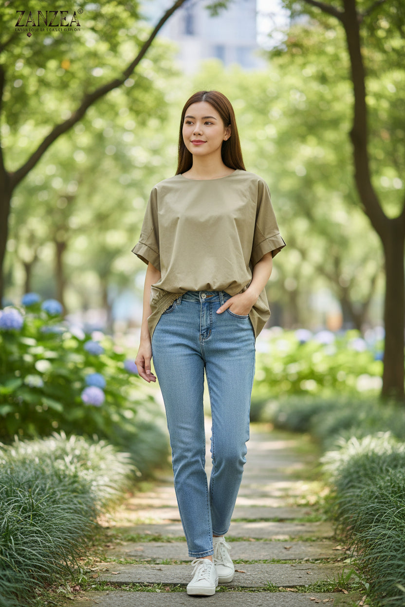 Beige blouse with rolled-up sleeves on a hanger against a white wall.