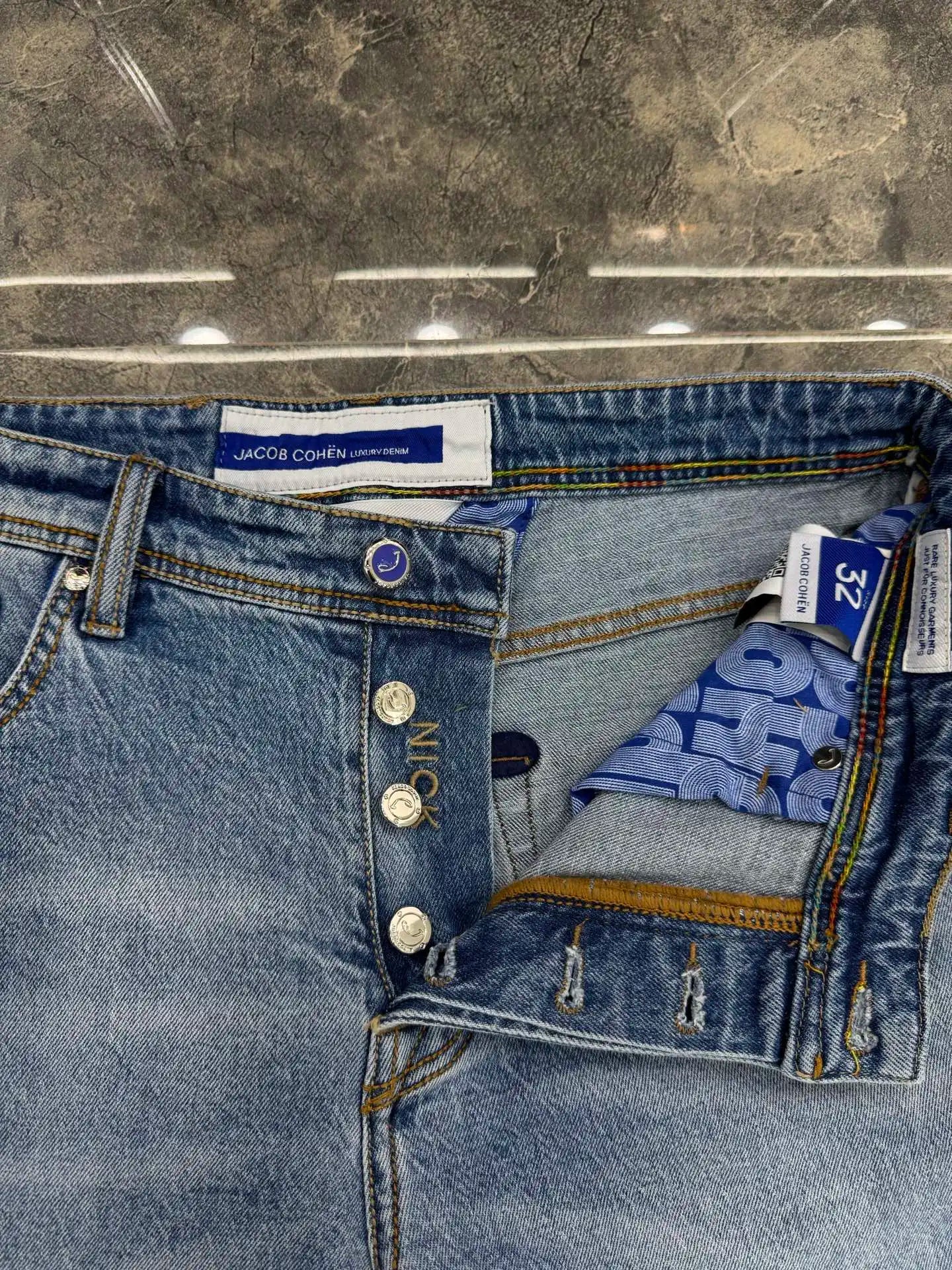 Close-up of blue jeans with brand label on a reflective surface