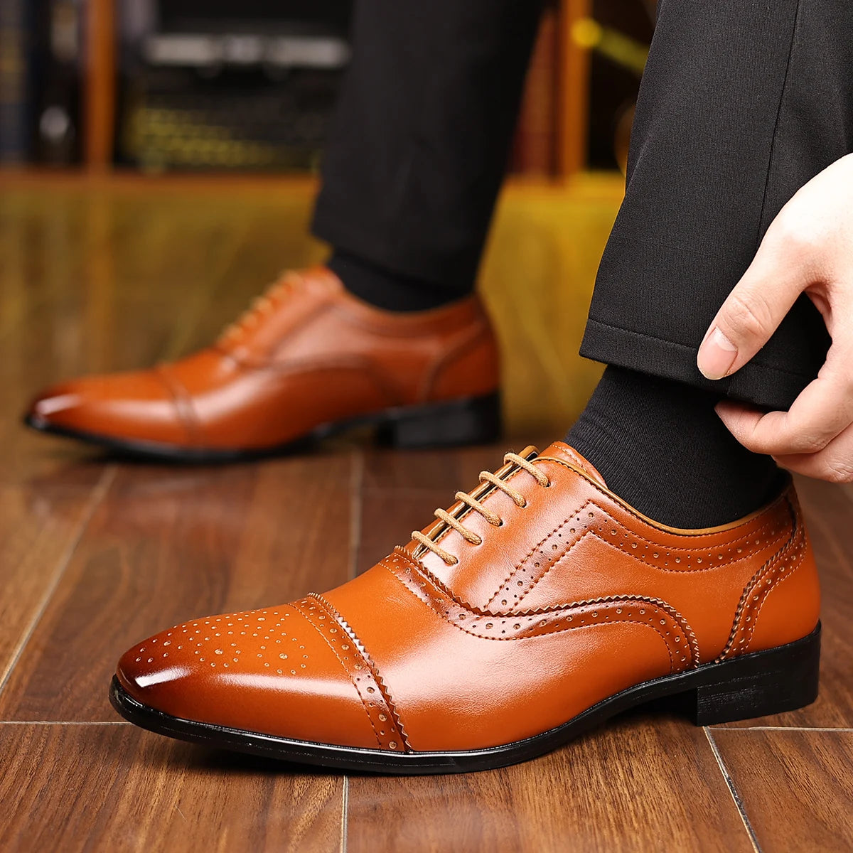 Brown dress shoes being worn on a wooden floor with a blurred background