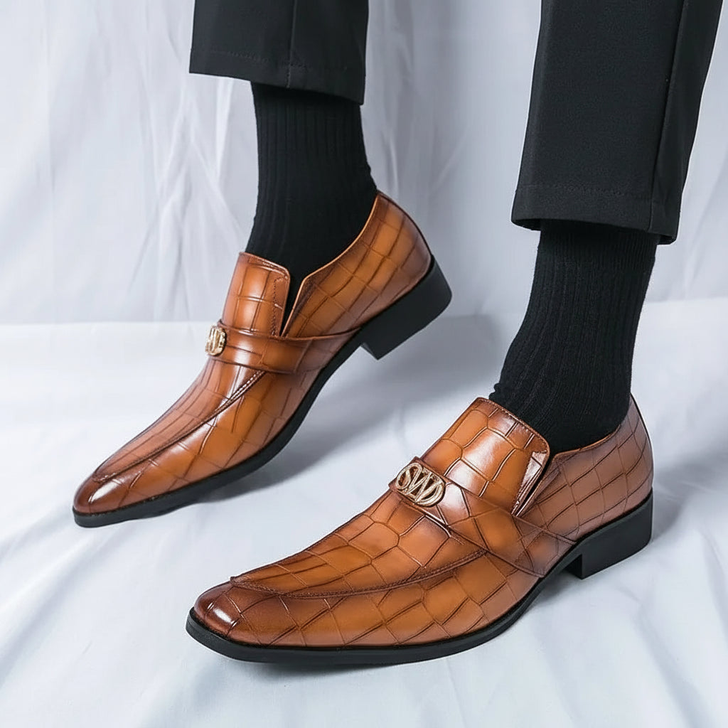 Brown leather shoes with gold accents worn by a person on a white background