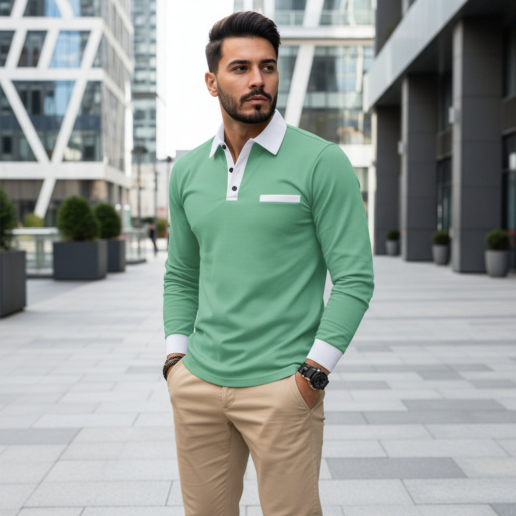 Man wearing a green long-sleeve polo shirt with white collar and cuffs, standing against a blurred background.