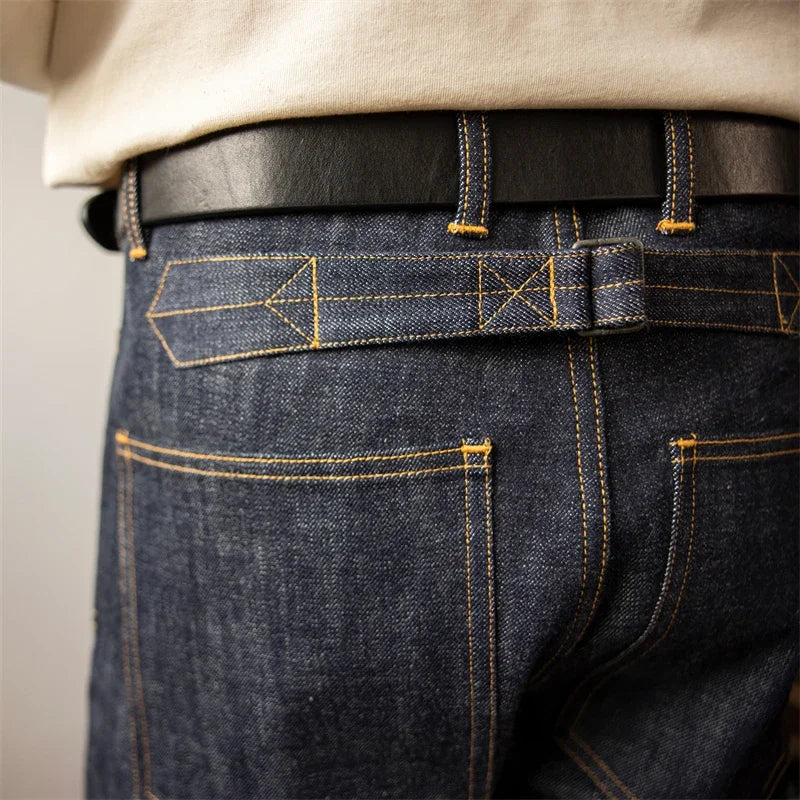 Close-up of dark blue jeans with yellow stitching on a plain background