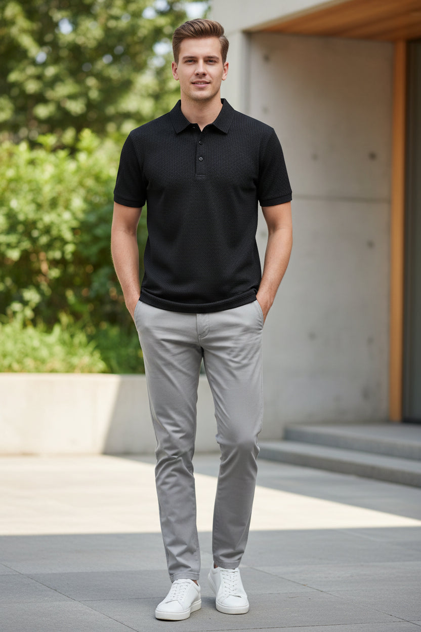 Black textured shirt on a hanger with a hand holding it