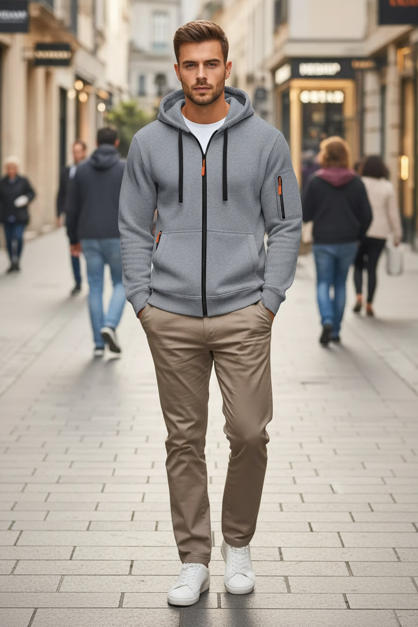 Man wearing a gray hoodie with orange accents on a blurred street background