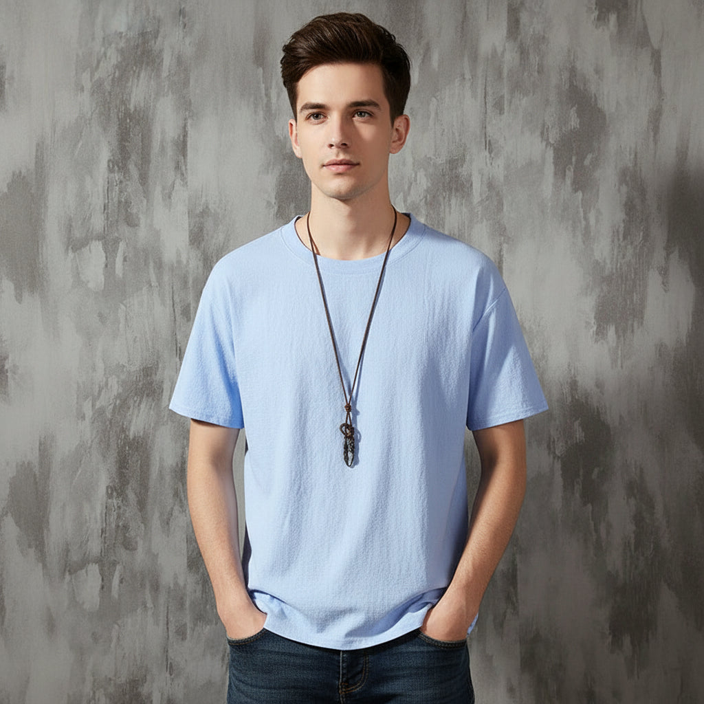 Light blue t-shirt on a hanger against a textured gray wall.